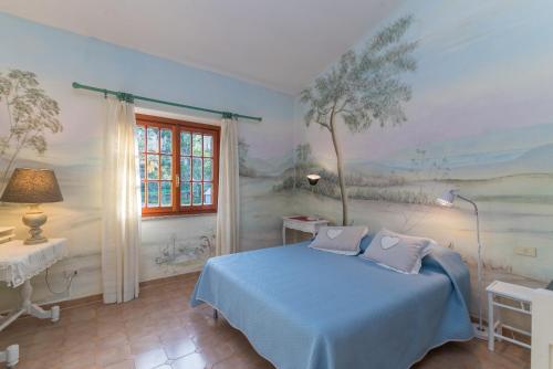 a bedroom with a blue bed and a painting on the wall at Villa Rosa sul mare in Olbia