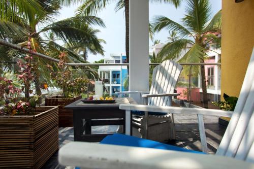 a balcony with two chairs and a table and palm trees at Owl and the Pussycat Hotel & Restaurant in Unawatuna