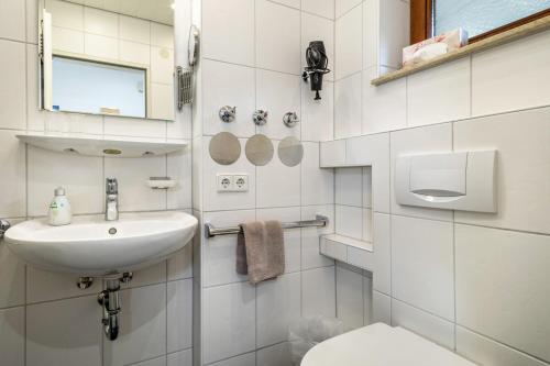 a white bathroom with a sink and a toilet at Gästehaus Heinemann - Eg3 in Langenargen