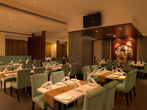 a dining room with tables and chairs and a television at Blu Petal - A Business Hotel in Bangalore