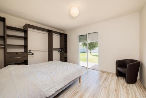a bedroom with a bed and a chair at Villa Lumière Ychoux in Ychoux