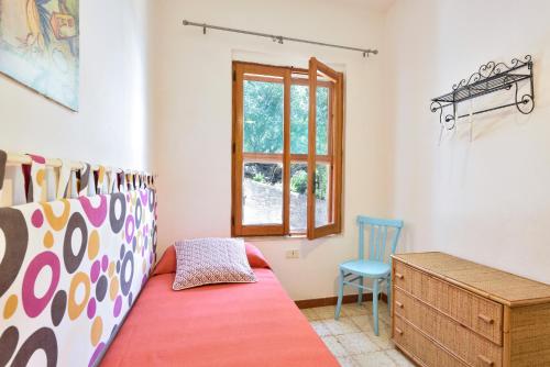a bedroom with a bed and a desk and a window at Casa Vacanze Osala in Orosei