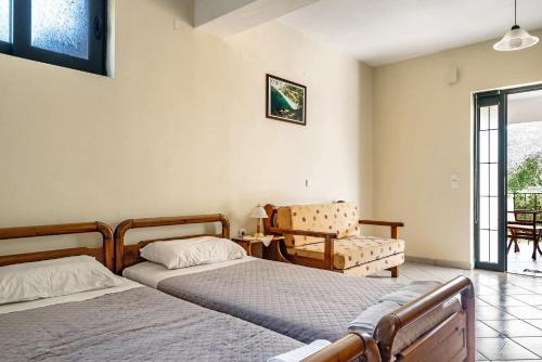 a bedroom with two beds and a chair at Daratos apartment 6 in Kefallonia