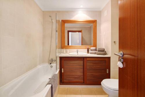 a bathroom with a tub and a sink and a toilet at Sunrise Salgados Village in Galé