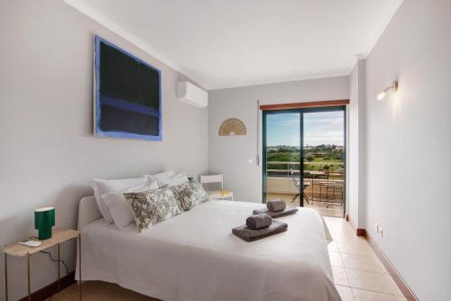 a white bedroom with a bed and a large window at Sunrise Salgados Village in Galé