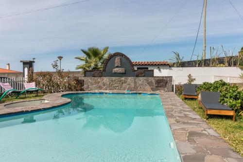 a swimming pool in a yard with a stone wall at Palmeira House - Fernandes Cottage in Ponta Delgada