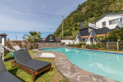 a swimming pool with a chaise lounge and a chair at Palmeira House - Fernandes Cottage in Ponta Delgada