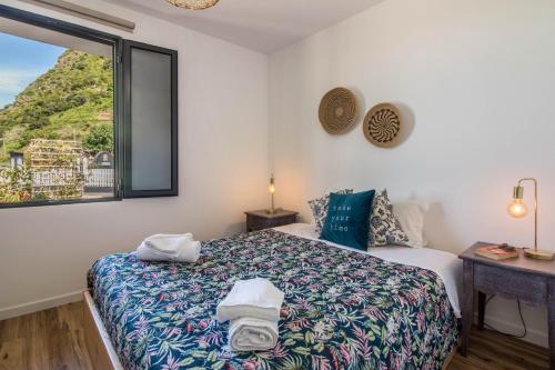 a bedroom with a bed and a window with a view at Palmeira House - Fernandes Cottage in Ponta Delgada