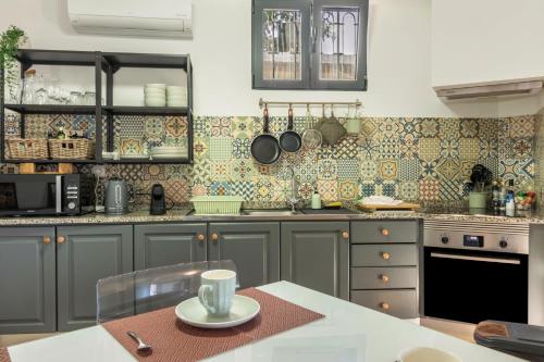a kitchen with gray cabinets and a table with a cup at Palmeira House - Fernandes Cottage in Ponta Delgada