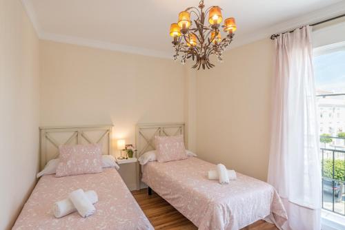 two beds in a bedroom with a chandelier at House Sun Beach 2 in Vejer de la Frontera