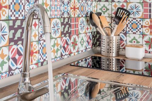 a kitchen with a chrome sink and a tile wall at House Sun Beach 2 in Vejer de la Frontera