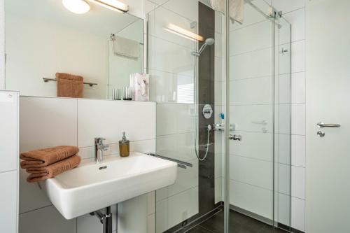 a white bathroom with a sink and a shower at Fink - Vogelhaus in Friedrichshafen