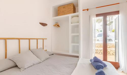 a white bedroom with a bed and a window at Villa Estrellas 2 in Cala en Bosc