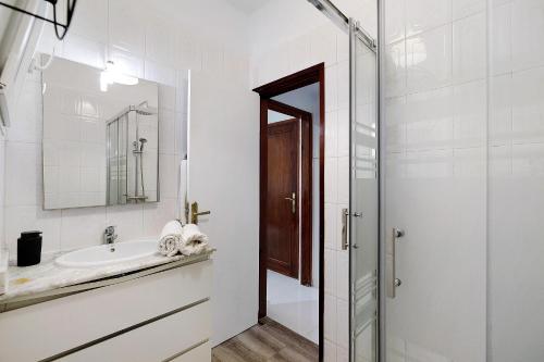 a white bathroom with a sink and a mirror at Piso Leon y Castillo B in Arrecife