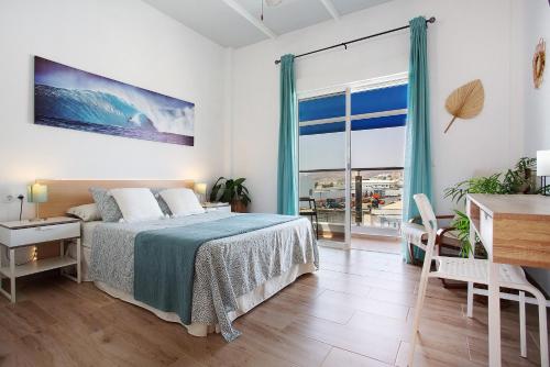a bedroom with a bed and a desk and a window at Alojamiento El Ocaso in Puerto del Rosario