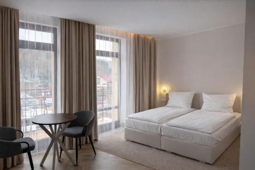 a bedroom with a white bed and a table and chairs at Willa Deptak in Krynica Zdrój