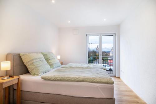 a white bedroom with a bed and a window at Fichte in Ravensburg