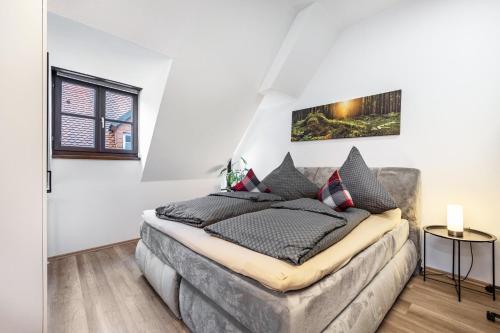 a bedroom with white walls and a bed with black pillows at Ferienwohnung Fernblick in Pottenstein