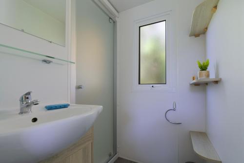 a white bathroom with a sink and a mirror at Mobilhome 373 in Lattes