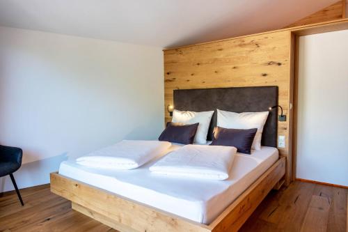 a bedroom with a large white bed with a wooden wall at Luisl Hof - Apartment Pomum in Cornaiano