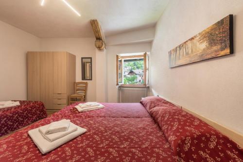 a bedroom with a red bed with two towels on it at Appartamento Glolo 2 in San Lorenzo in Banale