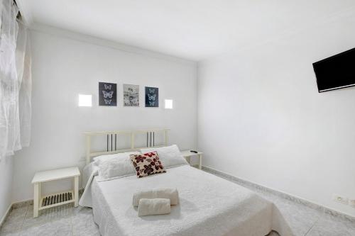 a white bedroom with a bed and a tv at Apartamento Mertxe in Arona