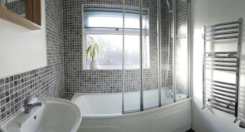 a bathroom with a tub and a sink and a window at Castle Cottage in Rayleigh