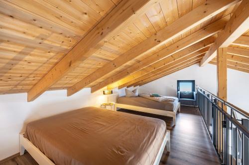 two beds in a room with wooden ceilings at Ferienhaus Sonnenwind Hainer See Og in Neukieritzsch