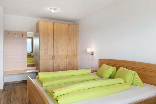 a bedroom with a bed with green pillows on it at Forchnerhof Apt Ploseblick in Maranza