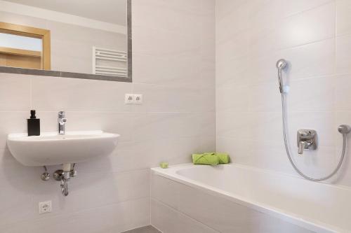 a white bathroom with a sink and a bath tub at Forchnerhof Apt Ploseblick in Maranza