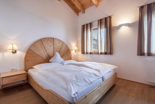 a bedroom with a large bed with a wooden headboard at Sabina Dolomites Birke in Alpe di Siusi