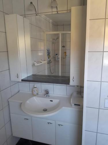 a white bathroom with a sink and a mirror at Ferienwohnung Heinz Romes in Wimbach