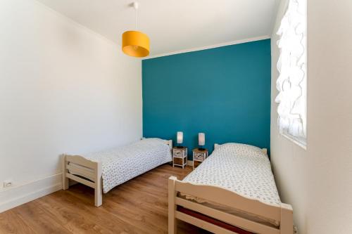 two beds in a room with a blue wall at Le Secret D'hestia in Bollène