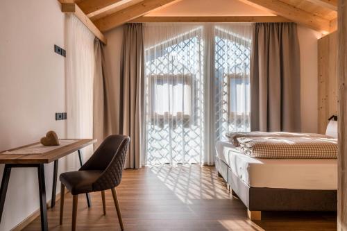 a bedroom with a bed and a desk and a window at Les Ciases Chalets Dolomites Apt 6 in San Vigilio Di Marebbe