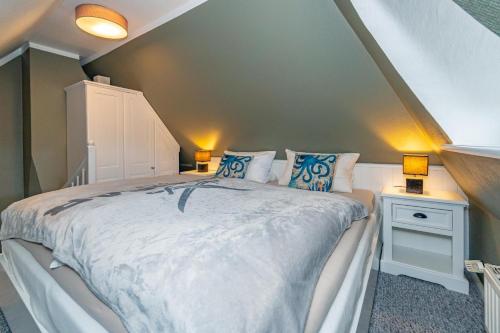 a bedroom with a large bed with blue pillows at Gemütliche Wohnung Reet-Pool-Sauna in Keitum