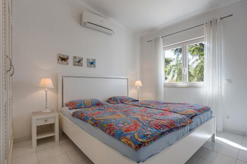 a white bedroom with a bed and a window at Villa Sagres in Portimão