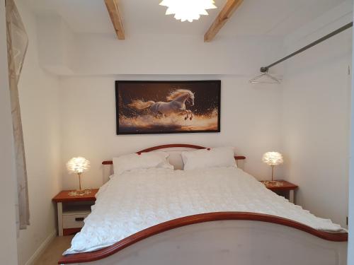 a bedroom with a white bed with a painting on the wall at Hochwertige Ferienwohnung in Lübeck