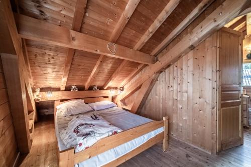 a bed in the middle of a wooden room at Chalet 6p Classique - L'ourson in Verchaix