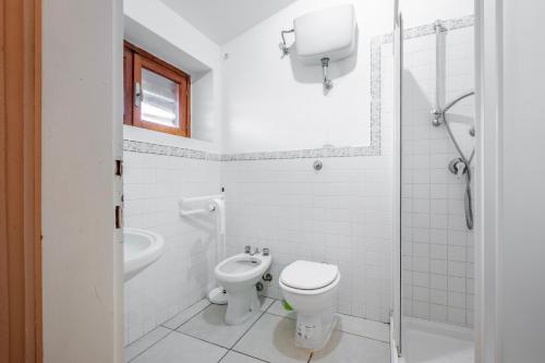 a white bathroom with a toilet and a sink at La Capannuccia B in Ansedónia