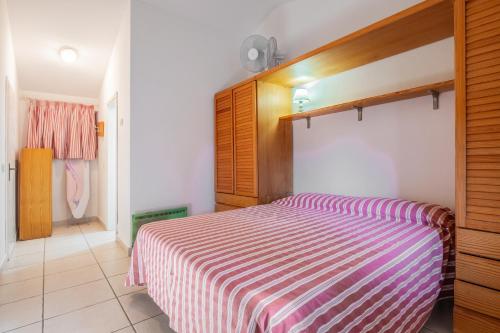 a bedroom with a pink and white striped bed at La Capannuccia B in Ansedónia