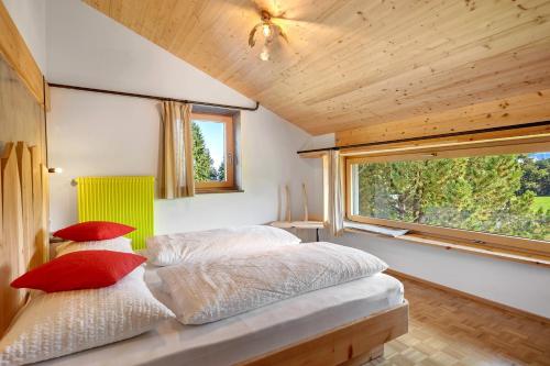 ein Schlafzimmer mit einem Bett mit roten Kissen und einem Fenster in der Unterkunft Kesselmoos in Deutschnofen