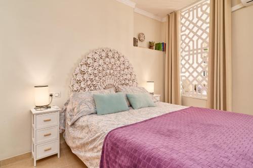 a bedroom with a bed with a purple bedspread and a window at Apartamento Fernandita in Nerja