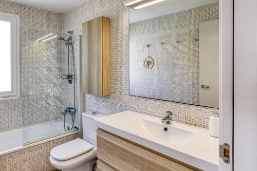 a bathroom with a sink and a toilet and a mirror at Pinamar casa con piscina in L'Escala