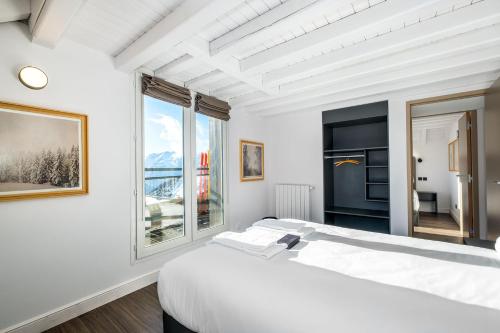 a white bedroom with a large bed and two windows at Triplex By Popalp in LʼHuez