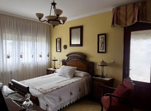 a bedroom with a bed and a chair and a window at Villa Neli Playa in Foz