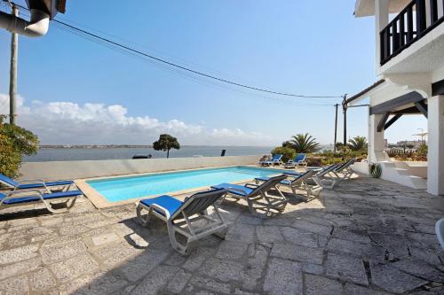 a swimming pool with chaise lounge chairs next to a house at Casa Do Bico Da Biarritz in Costa Nova