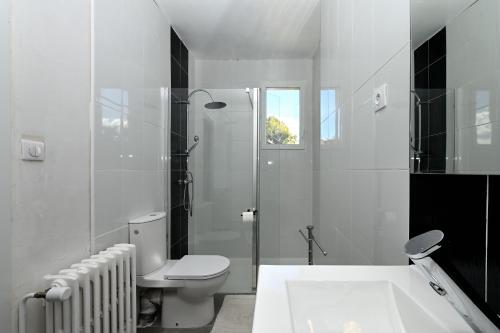 a white bathroom with a toilet and a bath tub at Villa Milady 2 in Salies-du-Salat