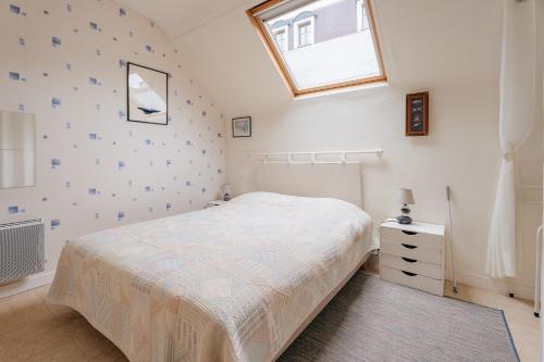 a white bedroom with a bed and a window at Appart Cancale Centre-ville - Mer in Cancale