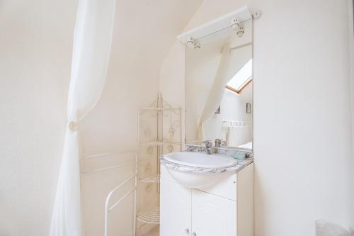 a white bathroom with a sink and a mirror at Appart Cancale Centre-ville - Mer in Cancale