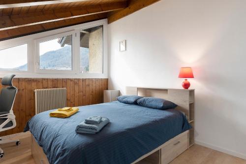 a bedroom with a bed with blue sheets and a window at Railway Loft Dimaro I By Immobilux in Monclassico
